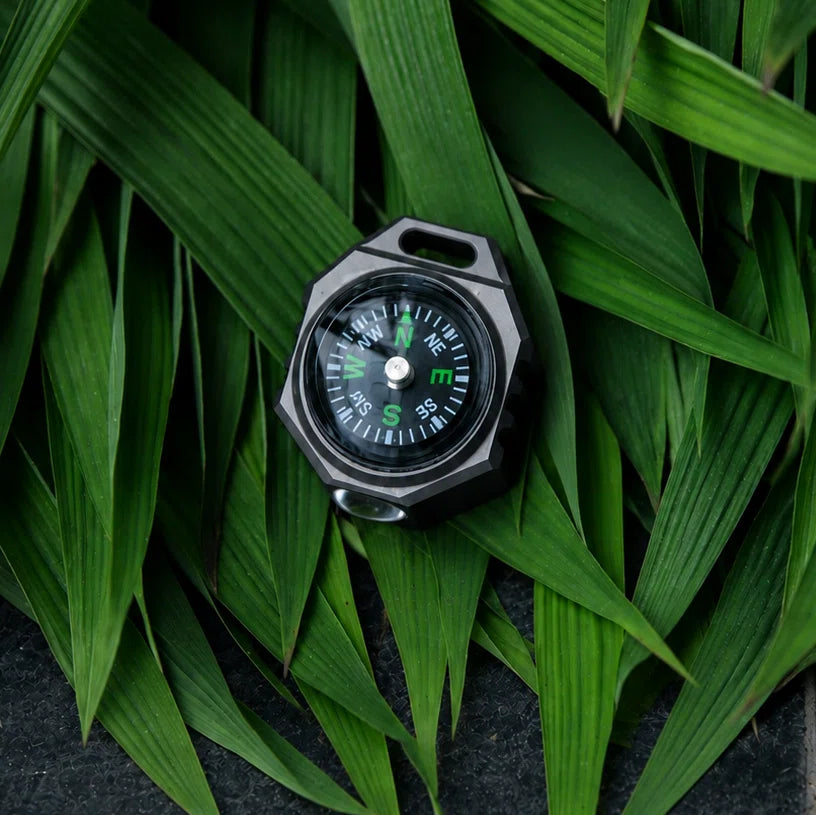 FIELDLUME T9 compact titanium EDC torch resting among green leaves