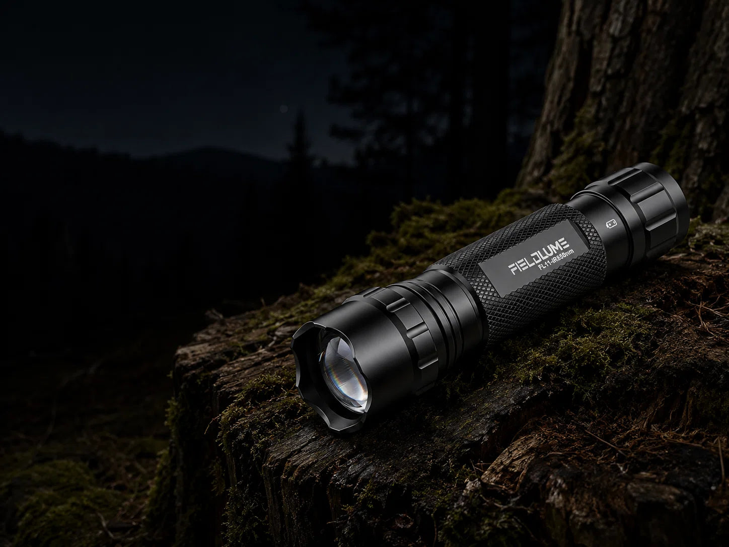 FIELDLUME FL11 850nm IR illuminator on a mossy tree stump in a dark outdoor setting